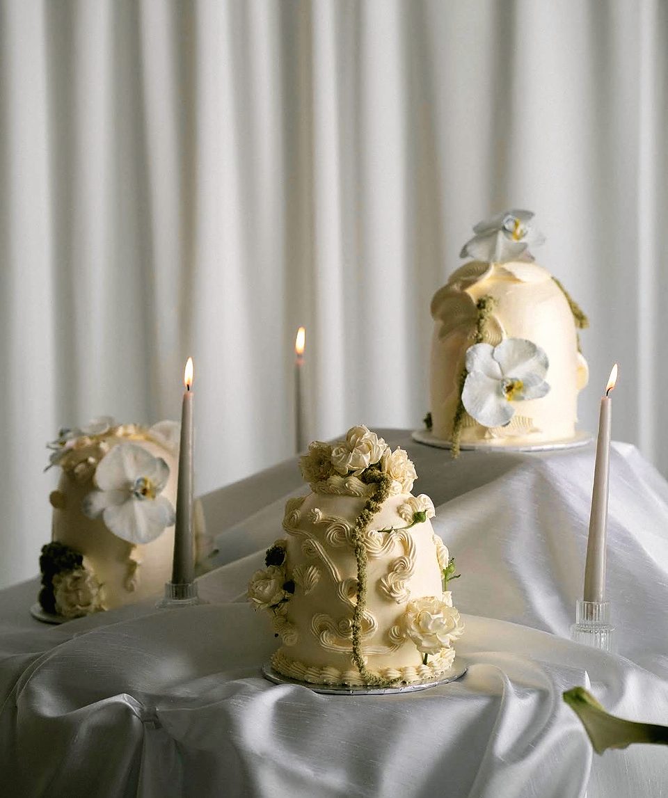 Three white bell-shaped cakes with taper candles